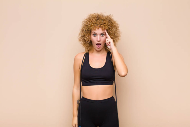 young afro woman looking surprised, open-mouthed, shocked, realizing a new thought, idea or concept sport concept - Фото, изображение