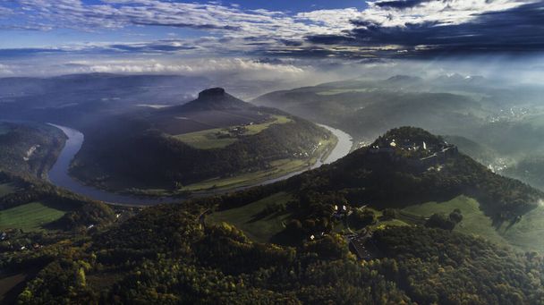 Konigstein Fortress - a Saxon mountain fortress near the town of Konigstein, located on a plateau rising 247 meters above the Elbe level, bathed in fog, aerial view - 写真・画像