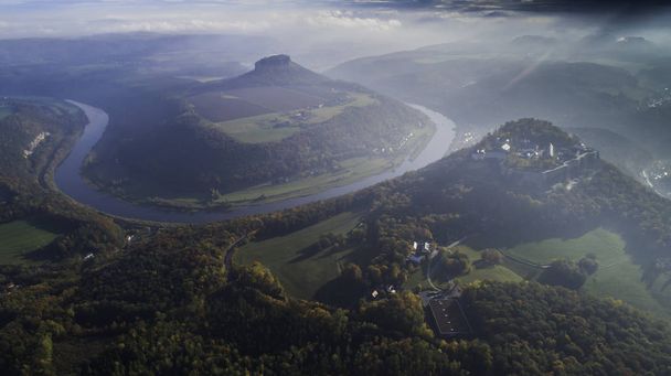 Konigsteinin linnoitus - saksien vuorilinnoitus lähellä Konigsteinin kaupunkia, joka sijaitsee tasangolla, joka nousee 247 metriä Elben tason yläpuolella, kylpee sumussa, ilmakuva
 - Valokuva, kuva