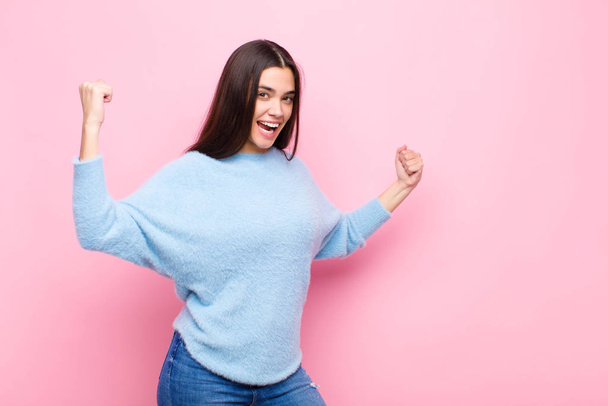 young pretty woman shouting triumphantly, looking like excited, happy and surprised winner, celebrating against pink wall - Fotoğraf, Görsel