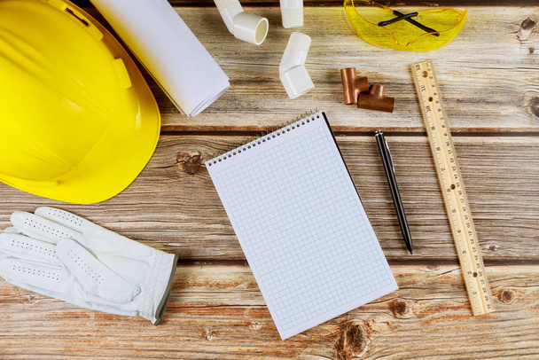 Construcción de edificios en planos con herramientas y casco en cuaderno con pluma con equipo de trabajo
 - Foto, Imagen