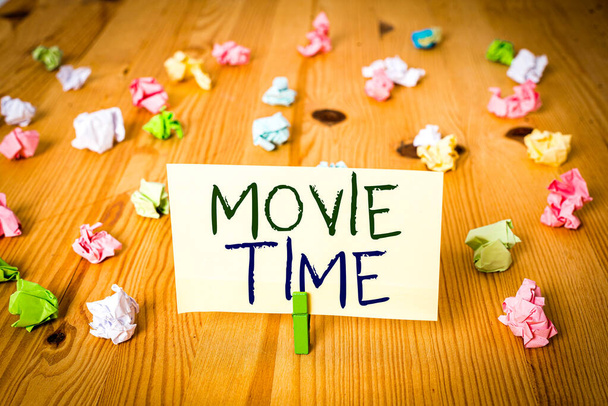Conceptual hand writing showing Movie Time. Concept meaning the scheduled or actual time at which a show or film begins Colored crumpled papers wooden floor background clothespin - Photo, Image