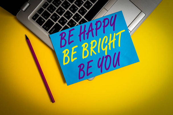 Fogalmi kézírás a Be Happy Be Bright Be You-ról. Koncepció jelentése Önbizalom jó hozzáállás élvezni vidám fém laptop kis papír lap ceruza színű háttér - Fotó, kép