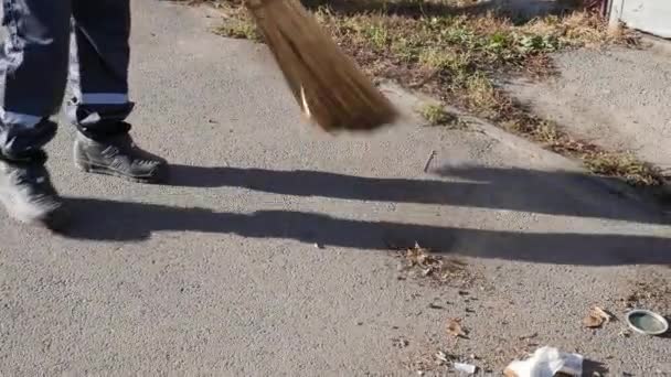 Janitor sweeping leaves in the street. Broom cleans the asphalt. Close up - Footage, Video