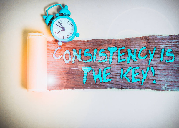 Handwriting text writing Consistency Is The Key. Conceptual photo by Breaking Bad Habits and Forming Good Ones Alarm clock and torn cardboard placed above a wooden classic table backdrop - Photo, Image