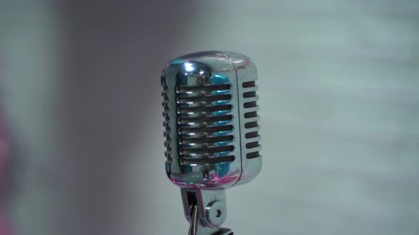 Zilveren vintage glare microfoon op het podium in retro club close-up. Licht schijnen op een mooie chroom retro mic op scène tegen op witte wazig achtergrond. - Video