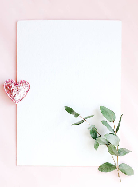 Hintergrund mit Leerzeichen auf rosa Hintergrund mit rosa glitzernden Herzen, Eukalyptuszweig. weiße Papieroberseite, flache Lage, minimalistischer Stil. Moke-up Karte. - Foto, Bild