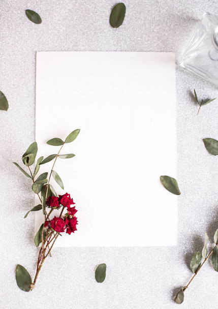 Achtergrond met kopieerruimte blanco op witte tafel met glitter hart, eucalyptus tak, bloemen en bladeren. Wit papieren bovenaanzicht, platte lay, minimale stijl. Moke up kaart. - Foto, afbeelding