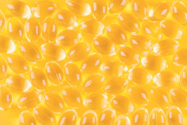 golden omega capsules on yellow background, closeup - Foto, Imagen