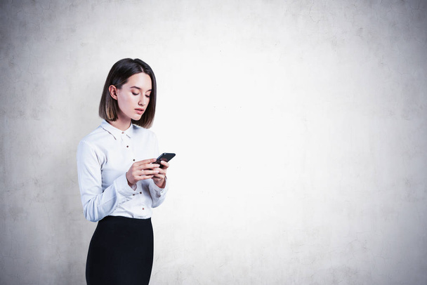 Serious young businesswoman with phone, mock up - Foto, Bild