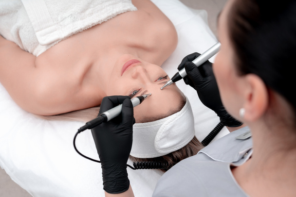 Kosmetologii. Piękna kobieta w spa Clinic odbieranie stymulowanie elektryczne leczenie twarzy od terapeuty. Zbliżenie młoda kobieta twarz podczas Microcurrent Therapy - Zdjęcie, obraz