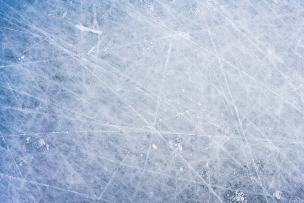 IJs achtergrond met merken van schaatsen en hockey, blauwe textuur van ijsbaan oppervlak met krassen - Foto, afbeelding
