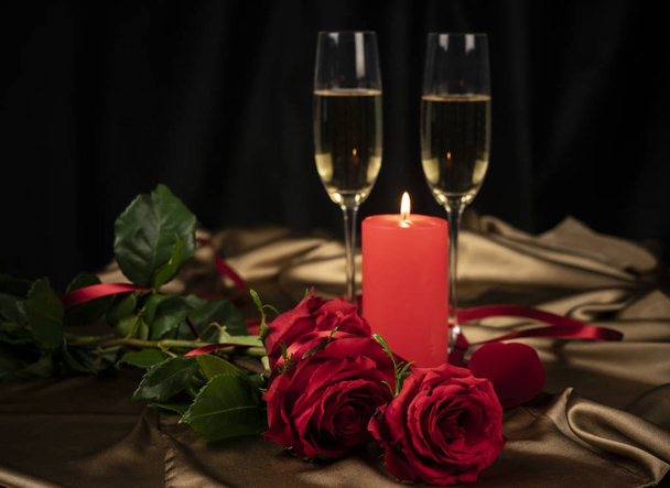 Sevgililer günü kartı, altın arka planda iki kadeh şampanya kırmızı güller ve kırmızı bir kalp, yanan bir mum. - Fotoğraf, Görsel