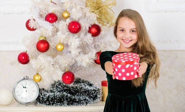 Child celebrate christmas at home. Favorite day of the year. Time to open christmas gifts. Merry christmas concept. Dreams come true. Best for our kids. Kid girl near christmas tree hold gift box - Photo, Image