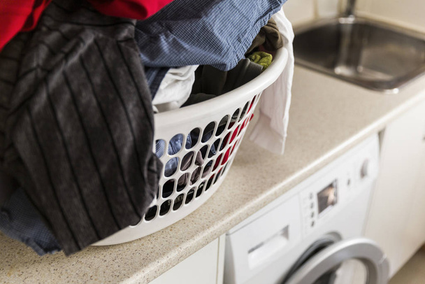 Cesta de lavado doméstica antes de colocar cerca en la lavadora
 - Foto, Imagen