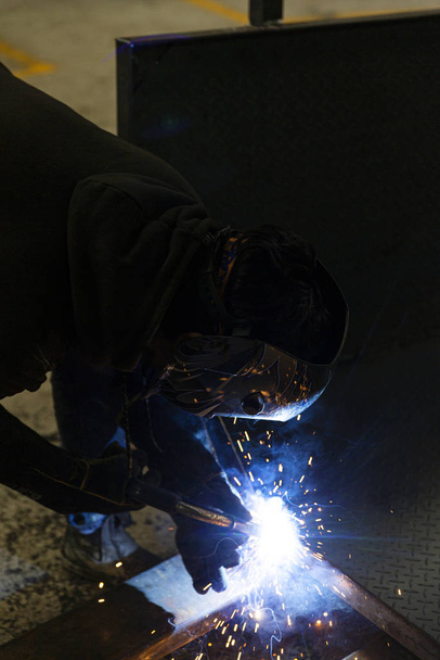 Jeune ouvrier soudant la barre métallique dans l'usine
 - Photo, image