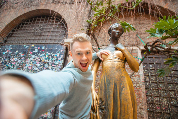 Selfie φωτογραφία του άνδρα που κρατά άγαλμα της Ιουλιέτας στήθος στη Βερόνα της Ιταλίας, χαμογελώντας και γελώντας. Ταξιδιωτική έννοια - Φωτογραφία, εικόνα