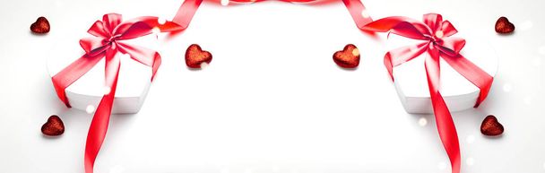 バレンタインデーの組成:弓と赤いリボンの心、写真テンプレート、背景と白いギフトボックス。コピースペース、ロマンスの季節の休日のトップビュー - 写真・画像