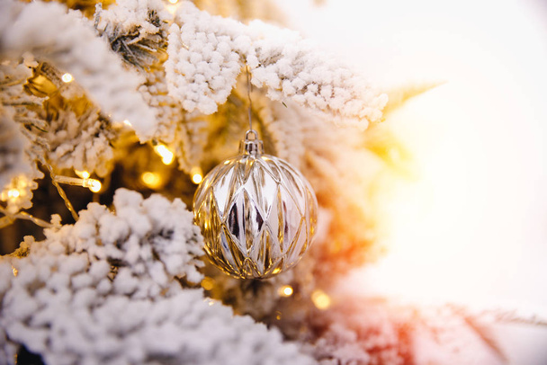 Fondo del árbol de Navidad con bolas de juguetes decorados con nieve artificial, iluminación de rama dorada
 - Foto, imagen