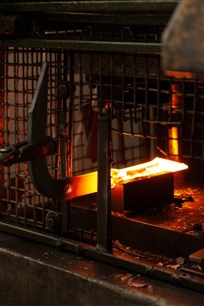 Barra de metal caliente ardiente que está siendo aprovechada en forma por el fabricante de metal
 - Foto, Imagen