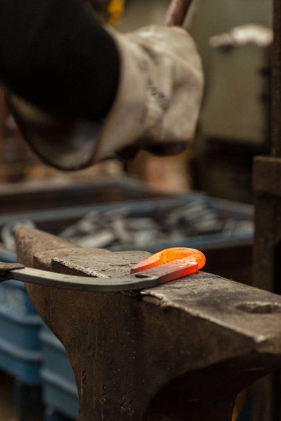 junger Schmied hämmert Metallhaken auf Amboss - Foto, Bild