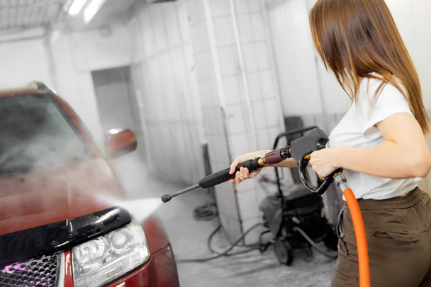 Car washing service. Worker woman cleaning auto using high pressure water - Photo, Image