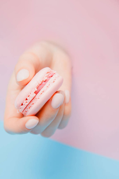 Stylish trendy female manicure on pink background. Girl holds hands macaron cookies through hole - Fotografie, Obrázek