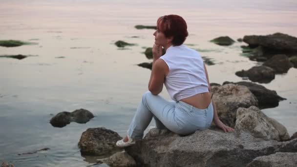 Жінка сидить на березі моря і посміхається
 - Кадри, відео