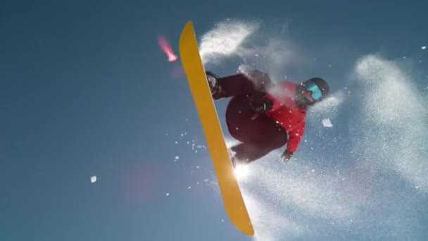 Slow Motion Close Up: snowboardista skákání a létání přes slunce na jasně modré obloze - Záběry, video