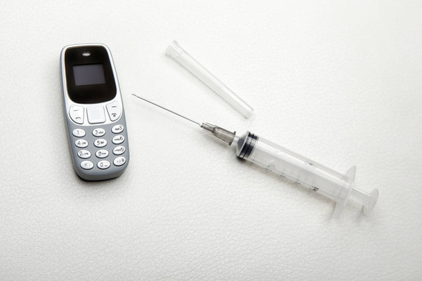 mobile phone syringe leather background  - Foto, immagini