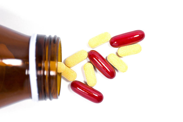 Medikamentenflasche, die Medikamentenpillen oder Vitamin auf weißem Hintergrund ausschüttet. - Foto, Bild