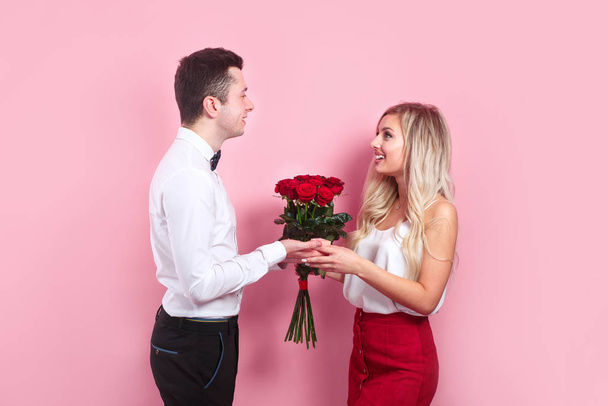 Handsome elegant boy is proposing to his beautiful girlfriend with her roses and smiling - 写真・画像