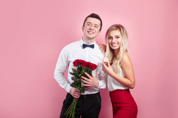 Attractive couple looking at camera and holding flowers - Foto, afbeelding