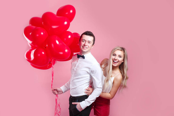 young loving couple with balloons heart on pink background - 写真・画像