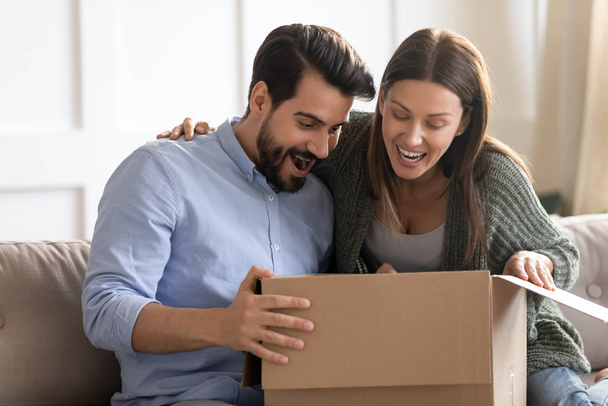 Excited millennial couple unpack internet order parcel - Fotó, kép