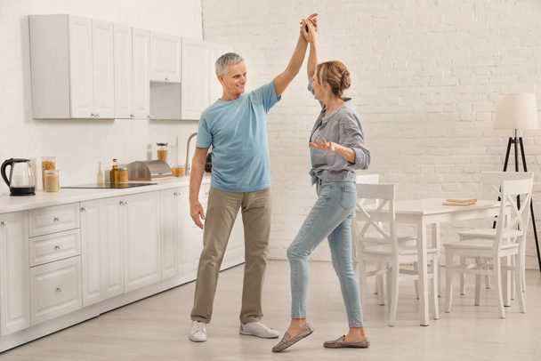 Happy senior couple dancing together in kitchen - Foto, afbeelding