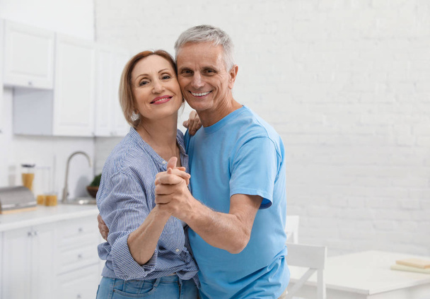 Happy senior couple dancing together in kitchen - Photo, Image