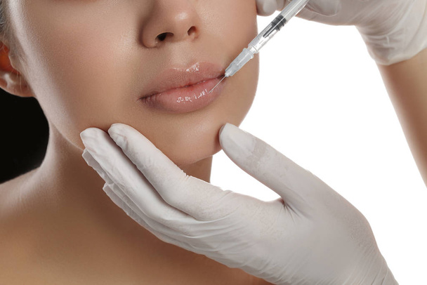 Mulher jovem recebendo injeção de lábios no fundo branco, close-up
 - Foto, Imagem