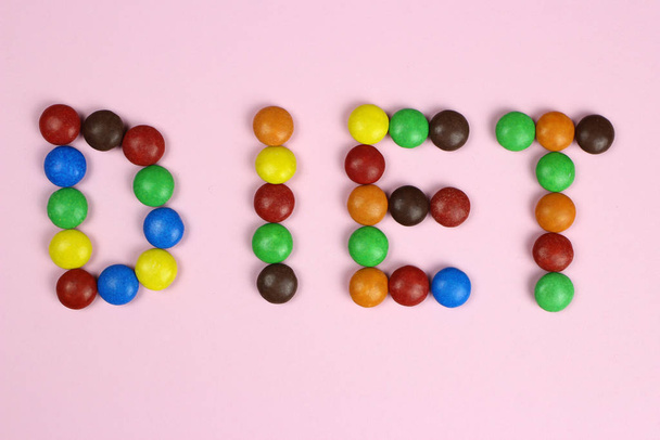 Diète Word de bonbons multicolores sur fond rose
 - Photo, image