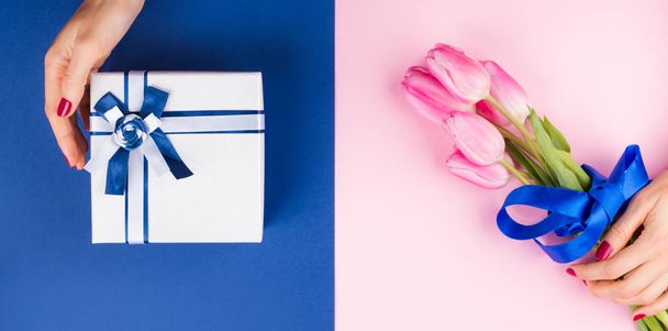 Female hand with tulips on pink and blue and gift - Fotoğraf, Görsel
