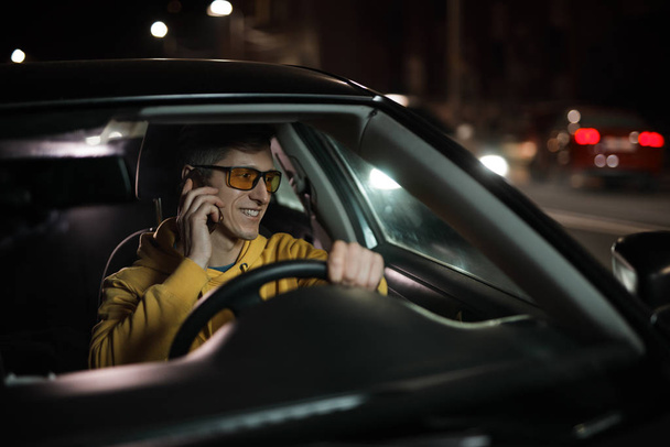 Driver man distracted to talking by mobile phone while driving car - 写真・画像