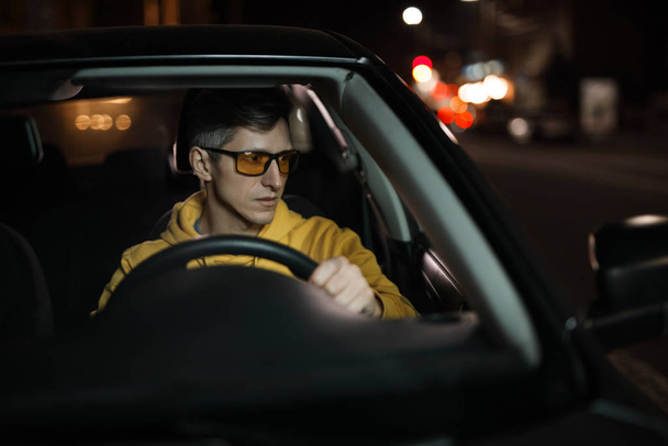 Man driving car in yellow eyeglasses at night - Foto, Imagem