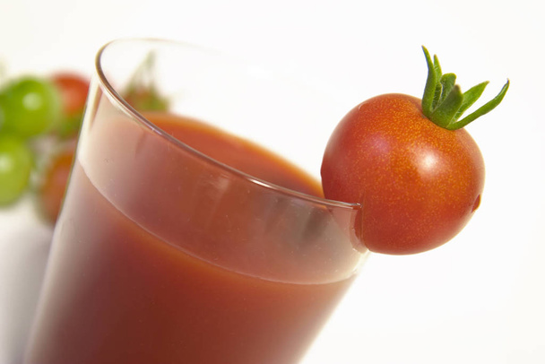 glass of tomato juice and fresh tomatoes on white background - Foto, afbeelding