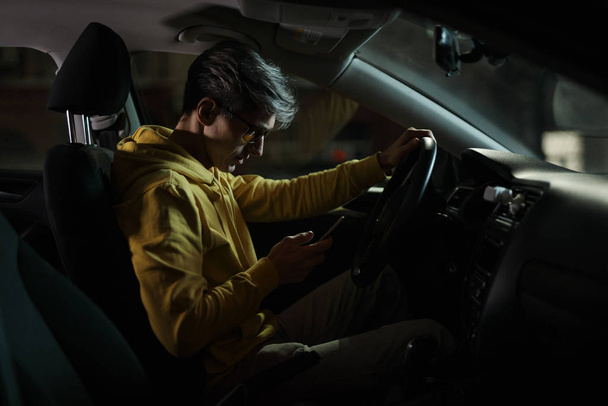 Driver man using mobile phone in car holder - Фото, изображение