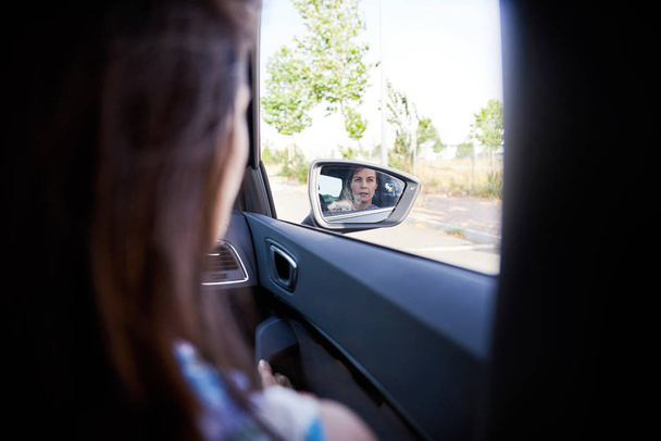 mulher viajando em um carro e olhando no espelho exterior
 - Foto, Imagem