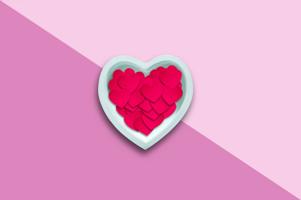 Paper hearts in a ceramic heart on a pink background .. Happy Valentines Day background. - 写真・画像