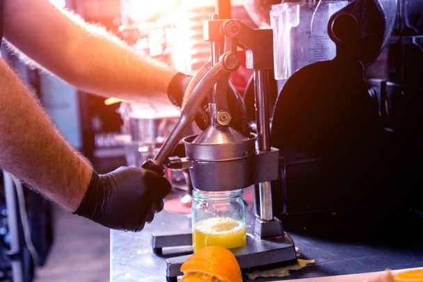 Metal manual juicer. Preparation of freshly squeezed orange juice - Foto, afbeelding