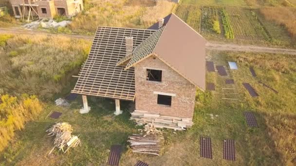 Luftaufnahme eines unfertigen Hauses mit Holzdachkonstruktion, die mit Blechen aus Metallziegeln bedeckt ist, die im Bau sind. - Filmmaterial, Video