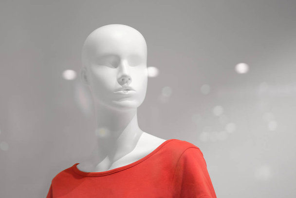 White mannequin in a red T-shirt on a grey background. - Фото, изображение