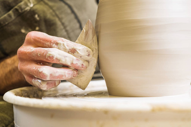 Potter w warsztacie tworzącym ceramiczny wazon na kole. Szczegóły dotyczące dłoni. - Zdjęcie, obraz